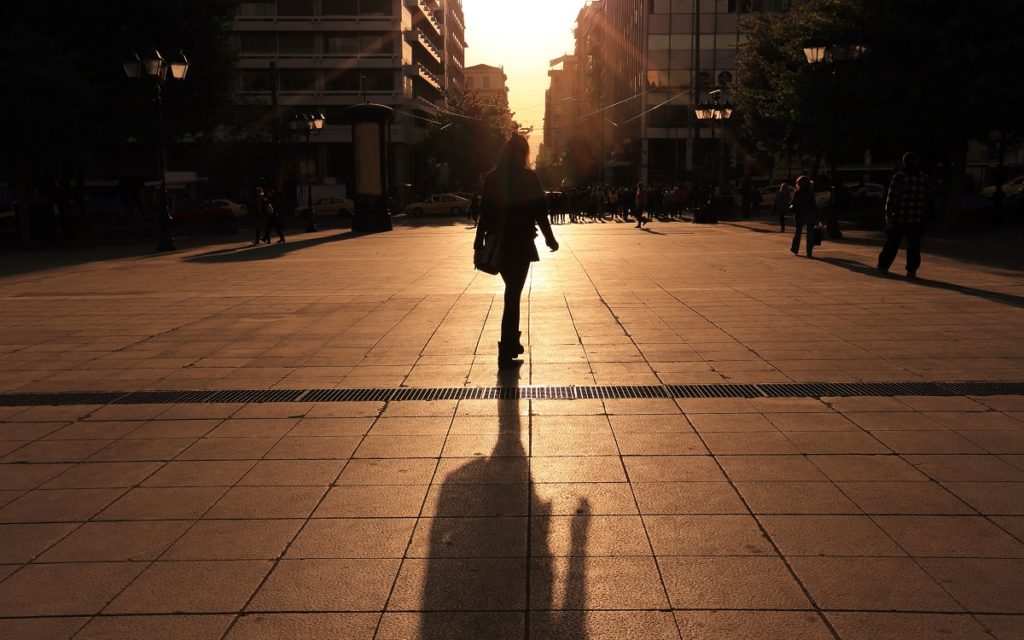 Person walking through a city on an evening with their shadow cast behind them