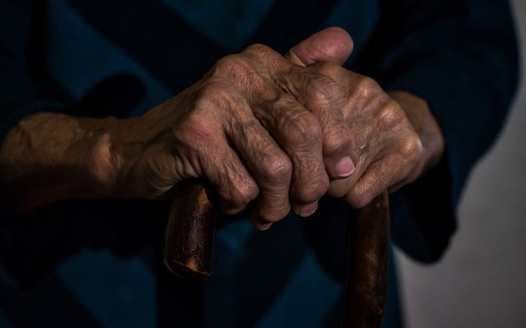 Elderly hands holding a walking stick