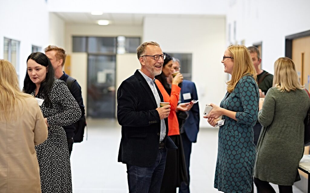 Several researchers stood in a corridor in conversation at an event