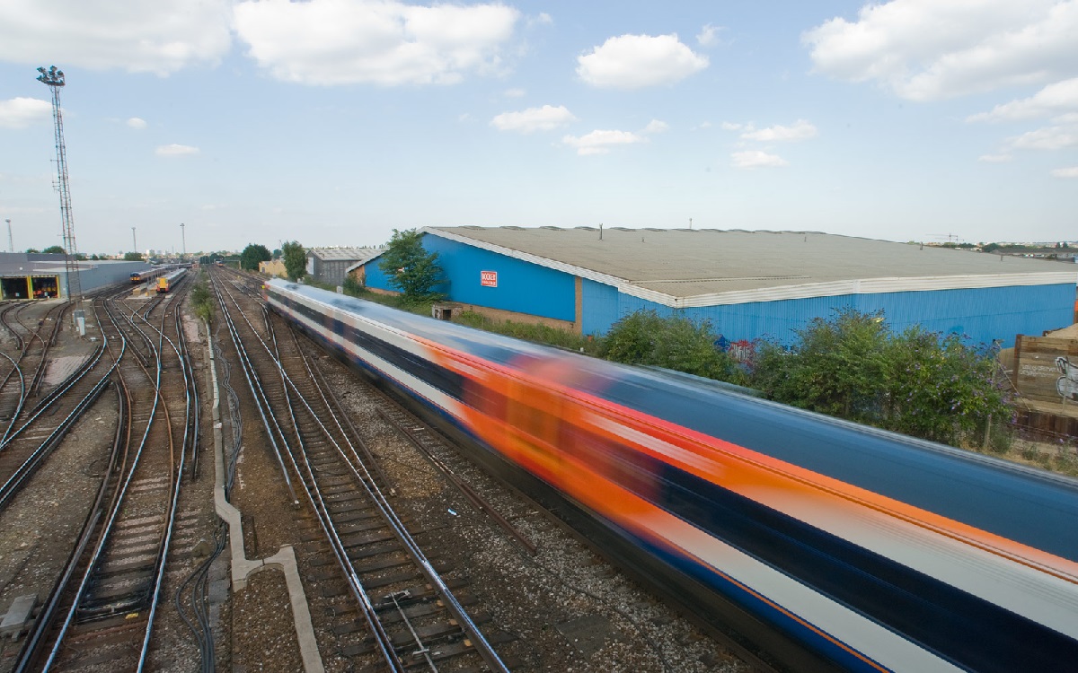 A white and orange train moving at speed on railway tracks