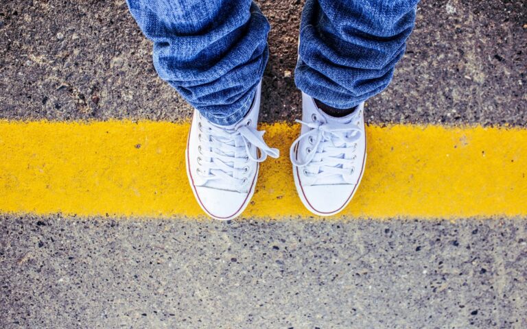 Person stood on yellow line with white shoes on