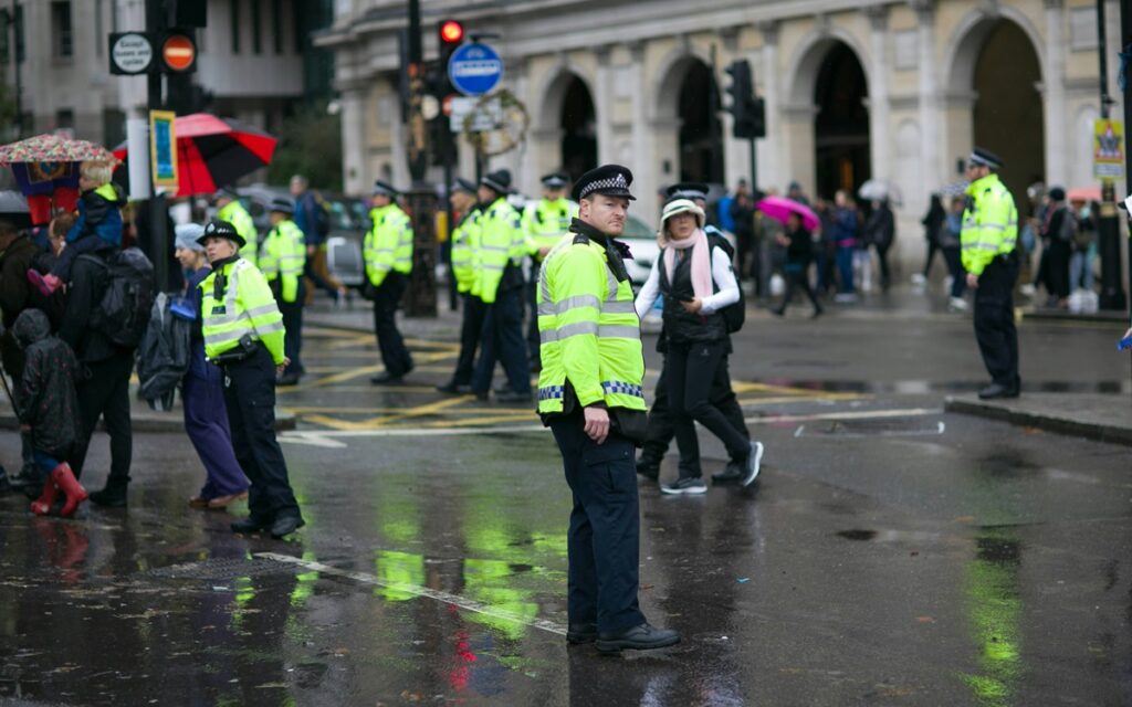 Police officers in hi-vis stood on the street among members of the public.