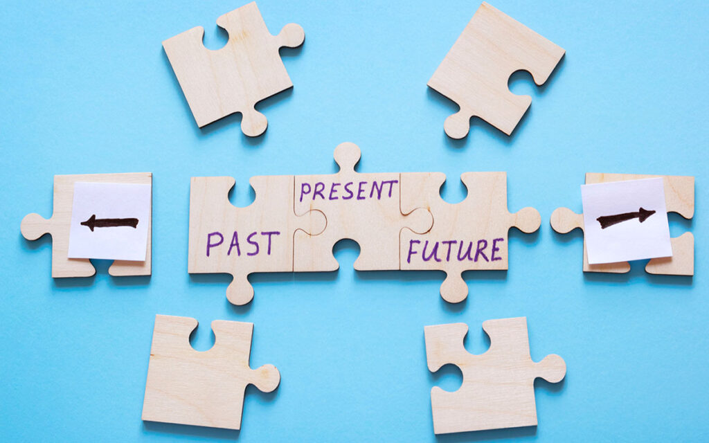 Jigsaw pieces with arrows and the words "past", "present" and "future" written on them.