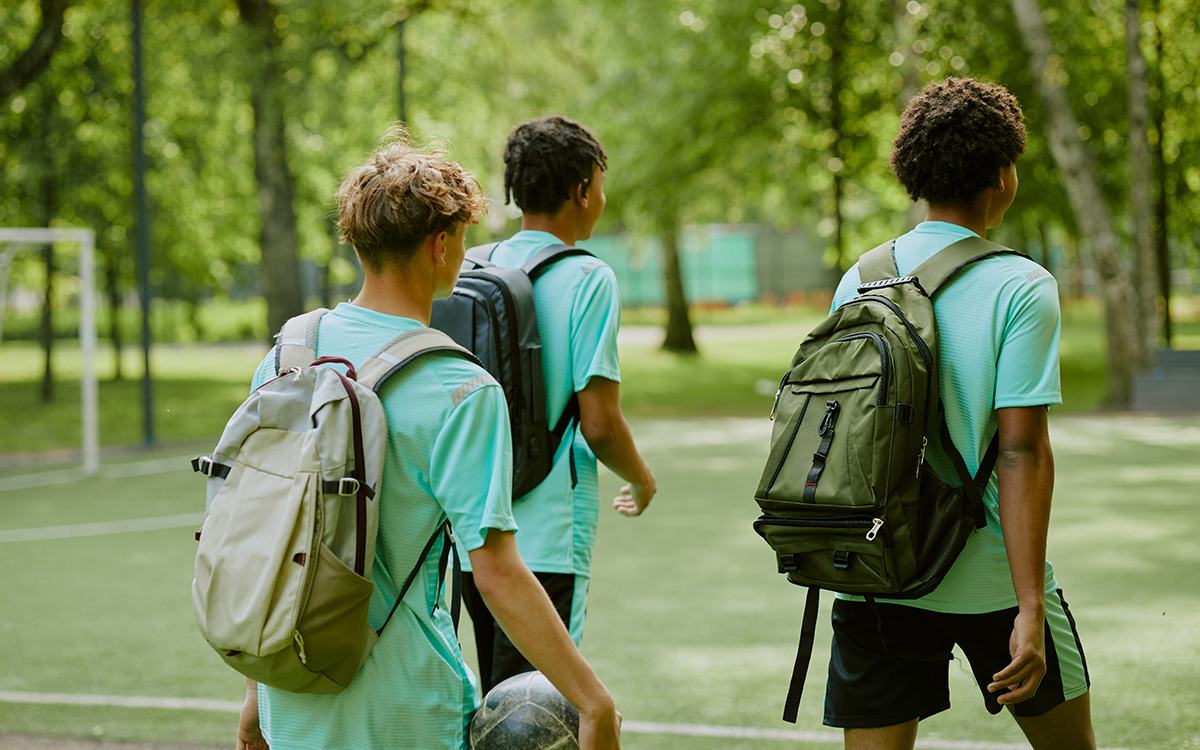 Group of teenage boys walking across a football pitch