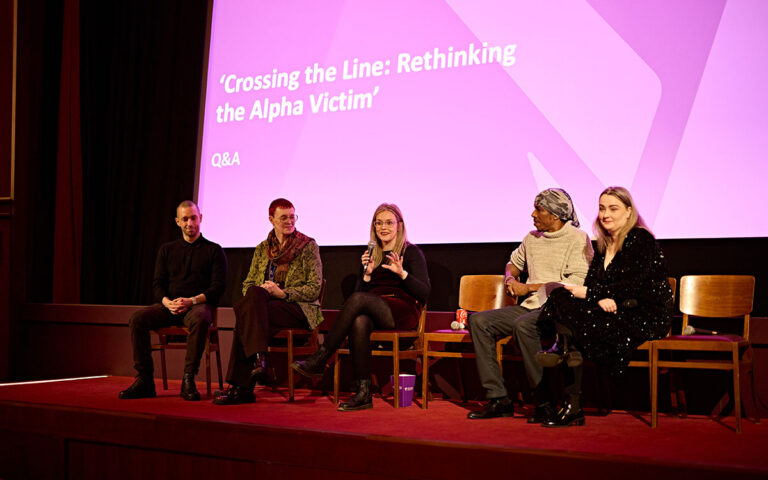 Panel members sat on chairs on stage in discussion at the Crossing the Line film premiere